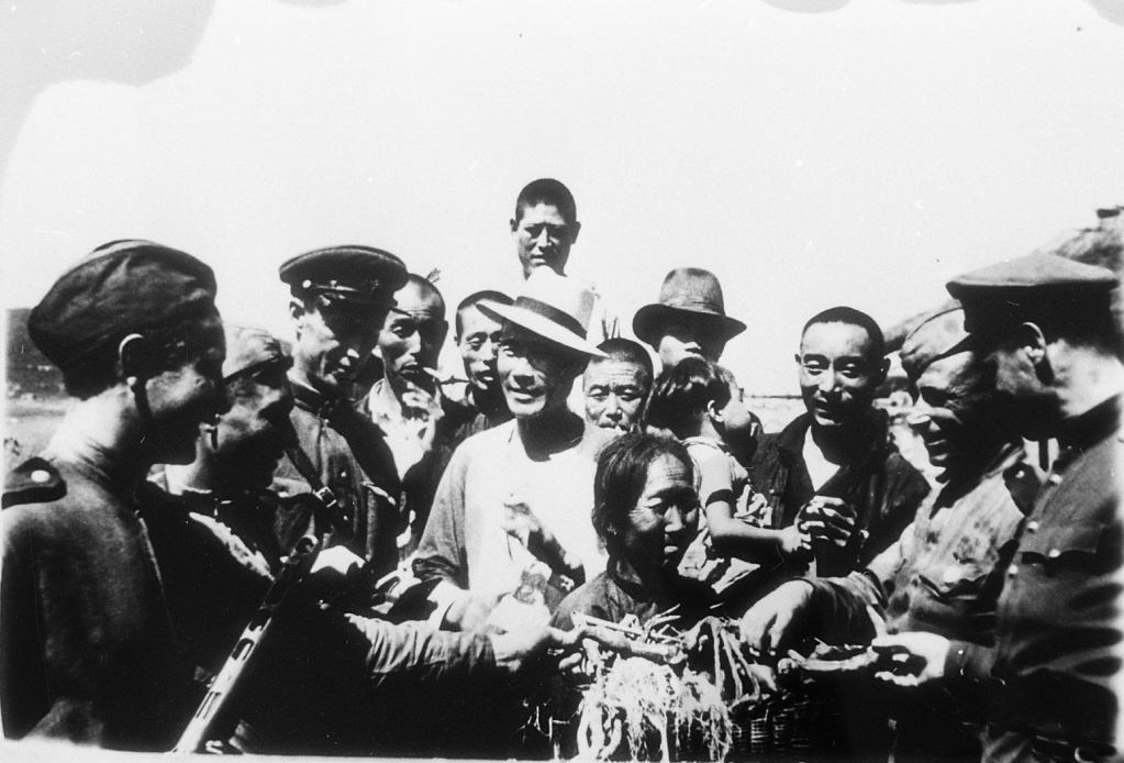 ГАПК. Фотофонд, 0-1084а. Жители г. Хлбэя (Маньчжурия) радостно встречают советских воинов, предлагая им огурцы, лук и др. овощи, г. Хэбэй, август 1945 г. В. Мясников 1.jpeg